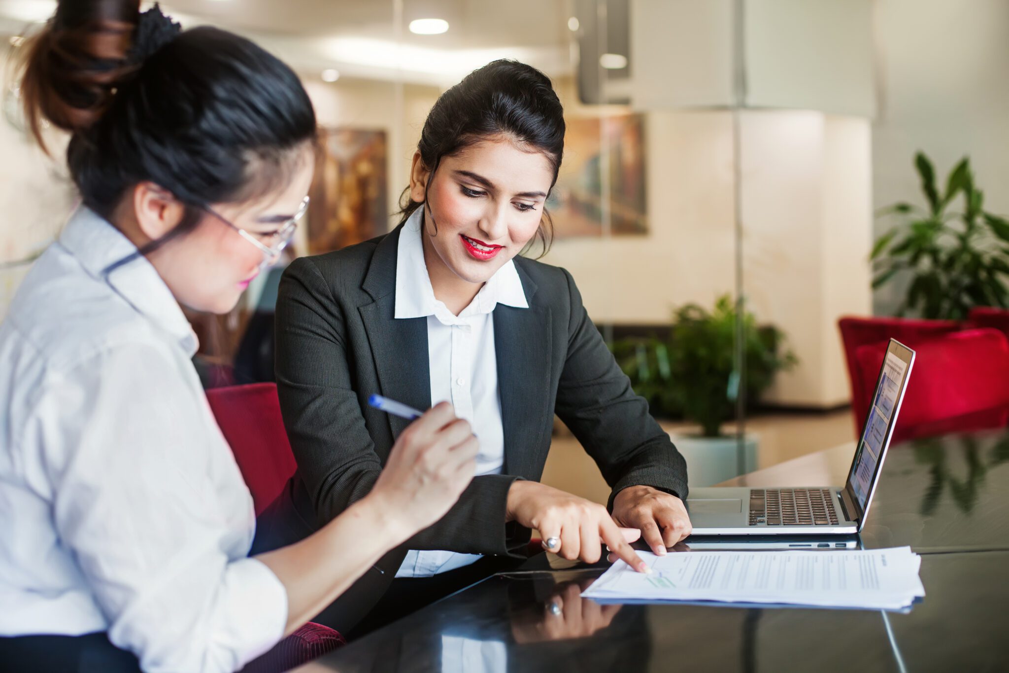 Two businesswomen collaborating over documents in an office.
