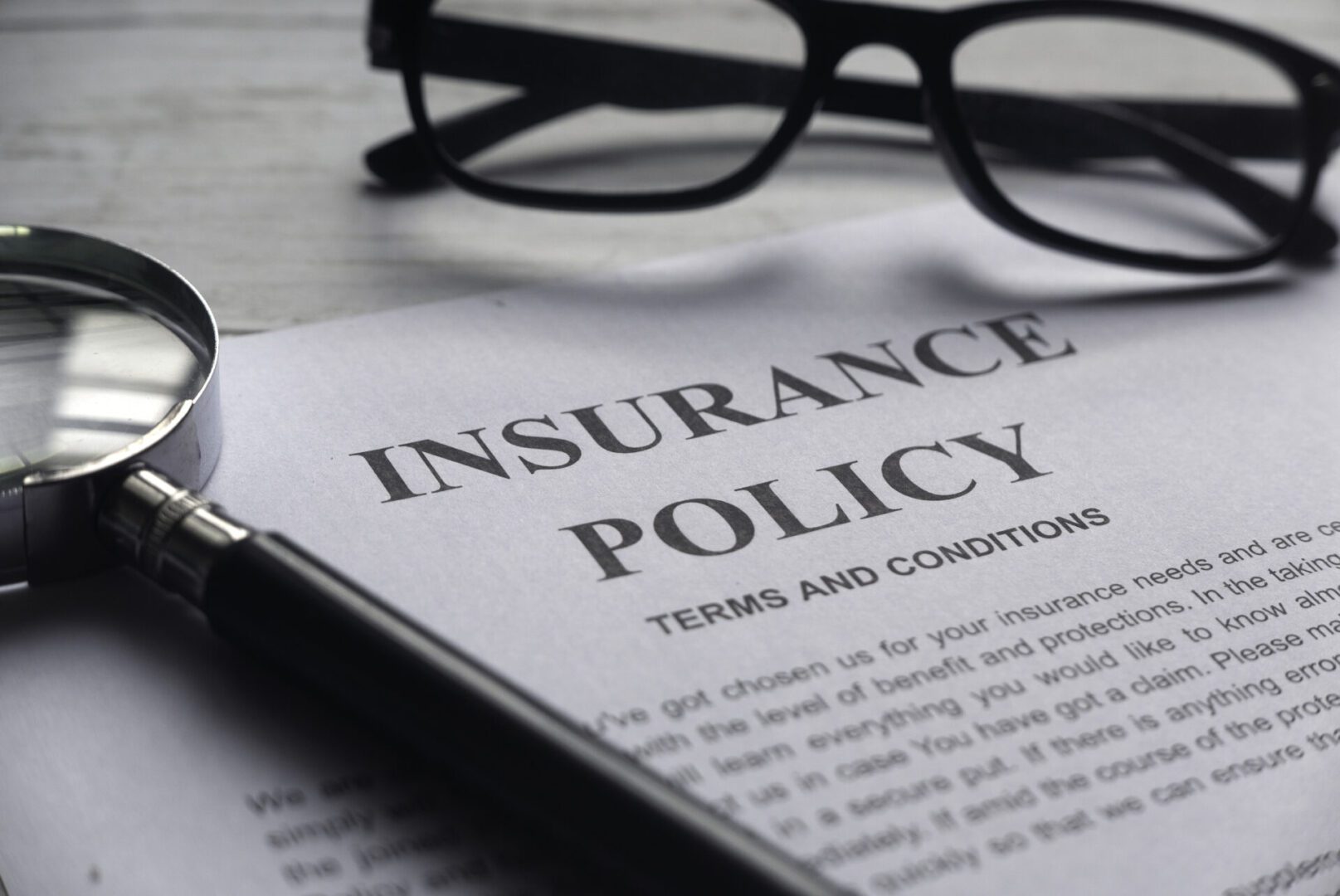 Close-up of an insurance policy document with glasses nearby.